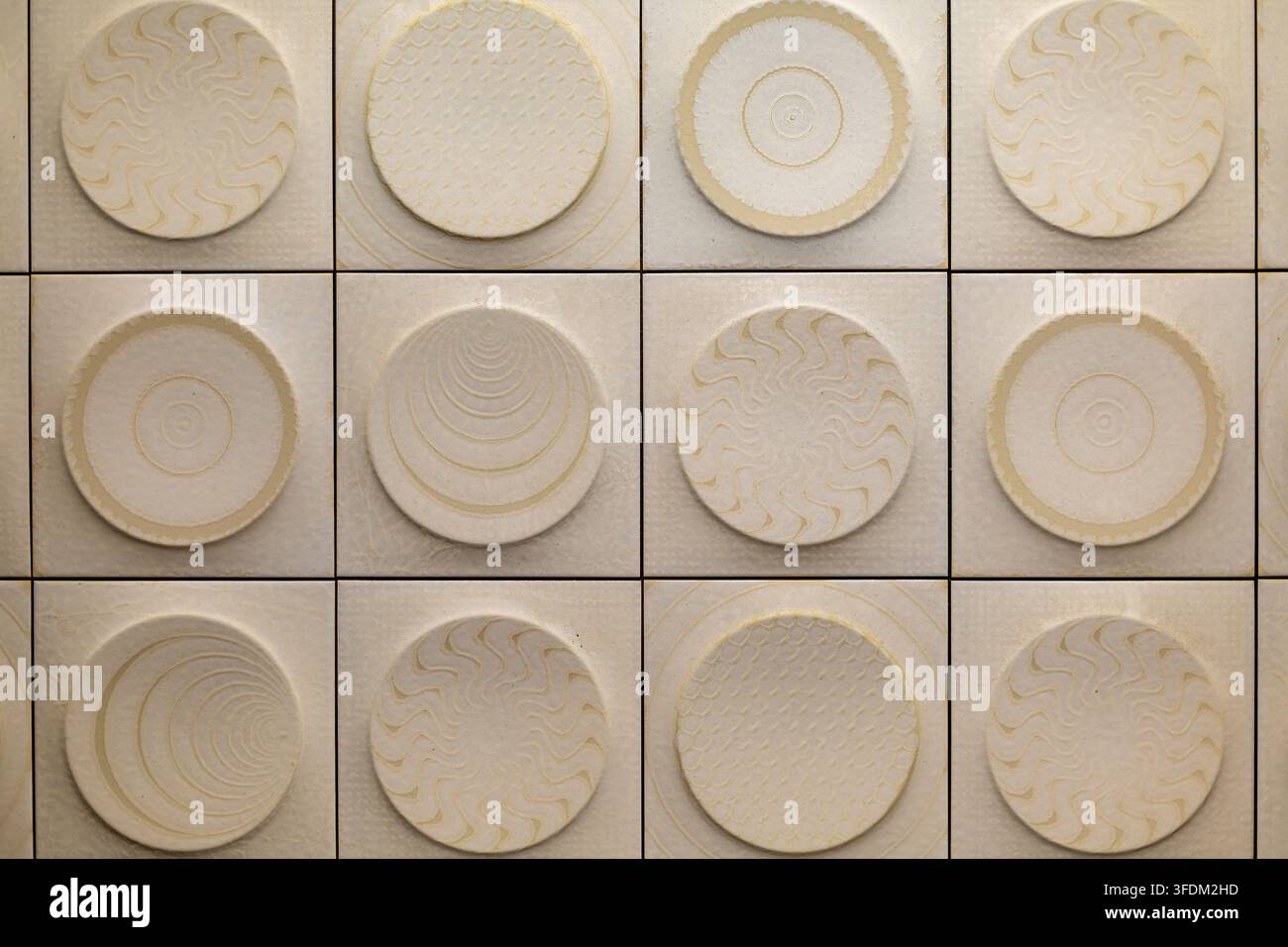 Motivo geometrico di piastrelle color crema con rilievi circolari. Piastrelle quadrate color crema con motivi circolari in rilievo che presentano onde, anelli, squame e cerchi concentrici Foto Stock