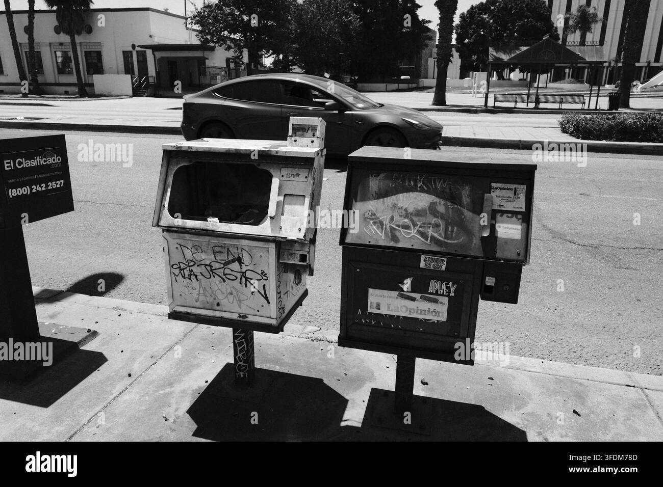 Distributori di giornali logorati lungo un marciapiede della California del Sud in una scena stradale in bianco e nero. Foto Stock