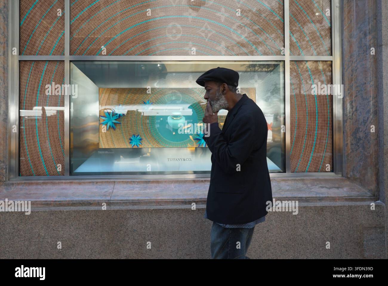 New York, New York, USA: Un uomo che fuma una sigaretta passa davanti alla vetrina di Tiffany & Co. sulla Fifth Avenue a Manhattan, New York City. Foto Stock