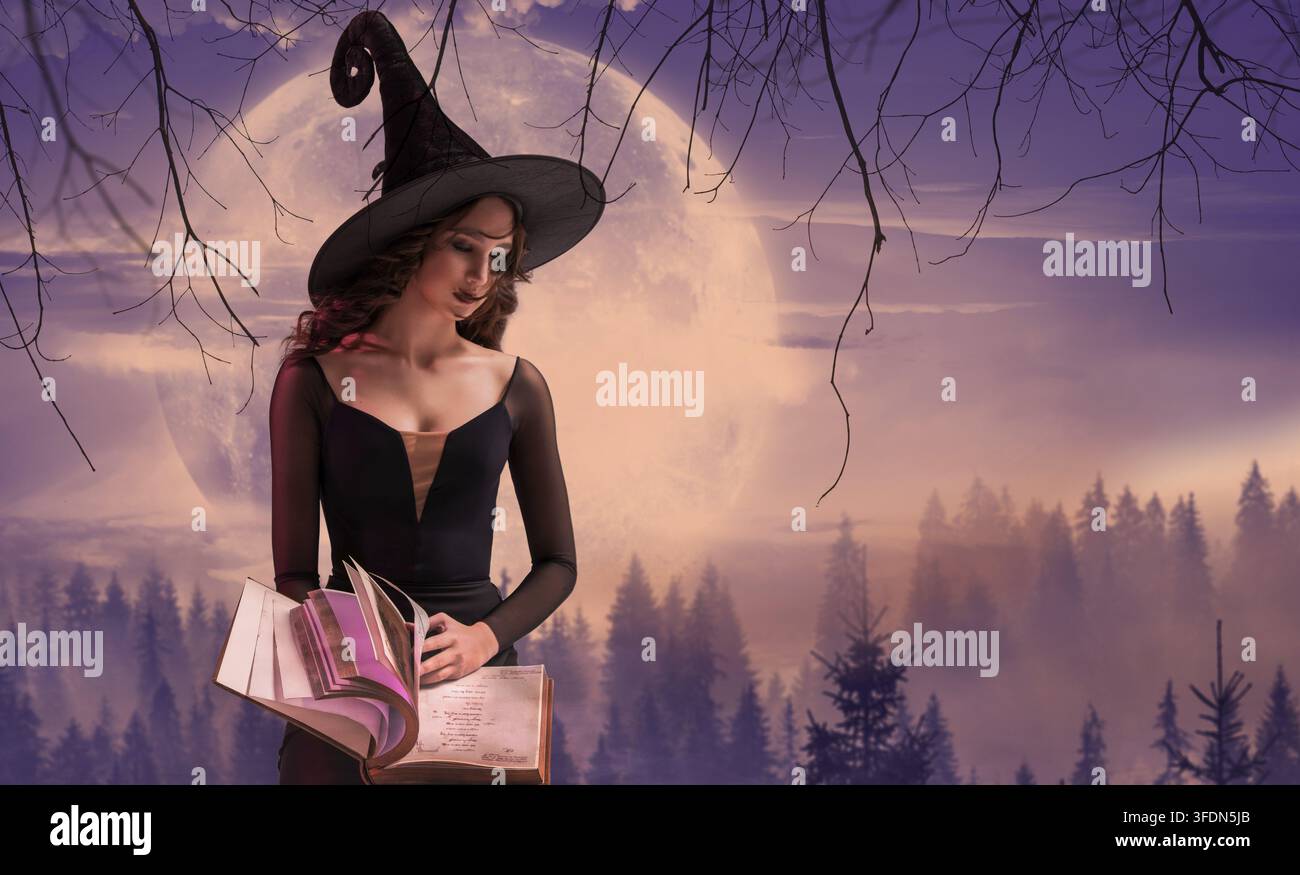 Strega di Halloween. Bella giovane donna con cappello da strega che evoca, pratica la stregoneria con un vecchio libro tra le mani sullo sfondo di enormi lillà Foto Stock