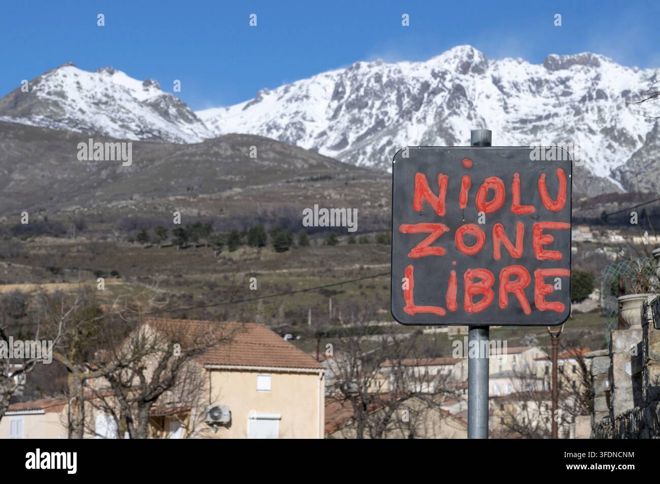 Un cartello con lo slogan politico dipinto a mano 'NIOLU ZONE LIBRE', che simboleggia l'identità regionale e la ricerca di autonomia, in primo piano aga Foto Stock