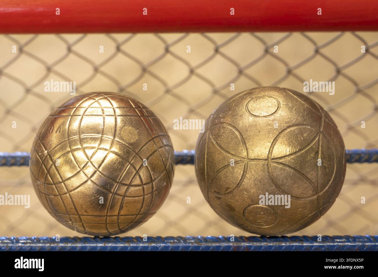 Due sfere di ottone incise per il tradizionale gioco della boule lyonnaise, una variante del gioco delle boules con sfere più grandi e pesanti, giacciono in primo piano su una ga Foto Stock
