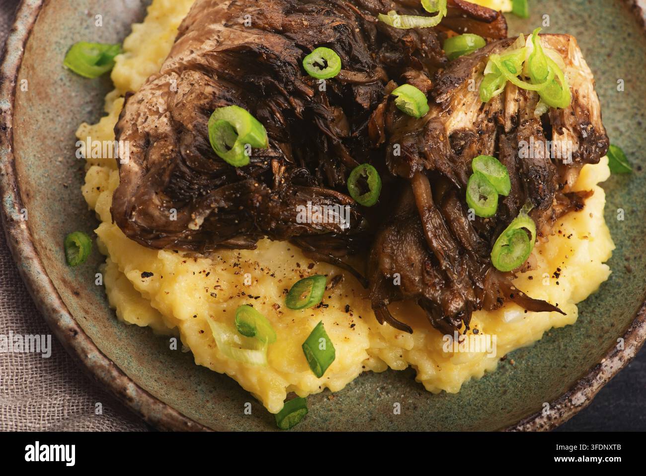 Funghi Maitake fritti su purè di patate con erba cipollina su un piatto di ceramica fatto a mano Foto Stock