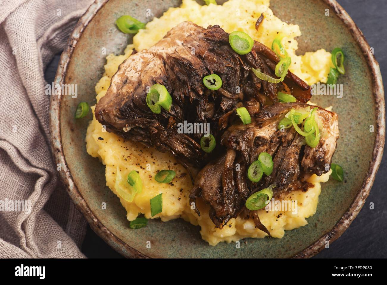 Funghi Maitake fritti su purè di patate con erba cipollina su un piatto di ceramica fatto a mano Foto Stock