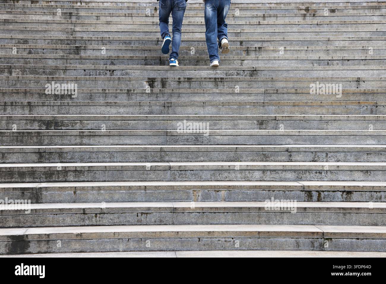 Due paia di gambe che salgono una rampa di scale di pietra Foto Stock