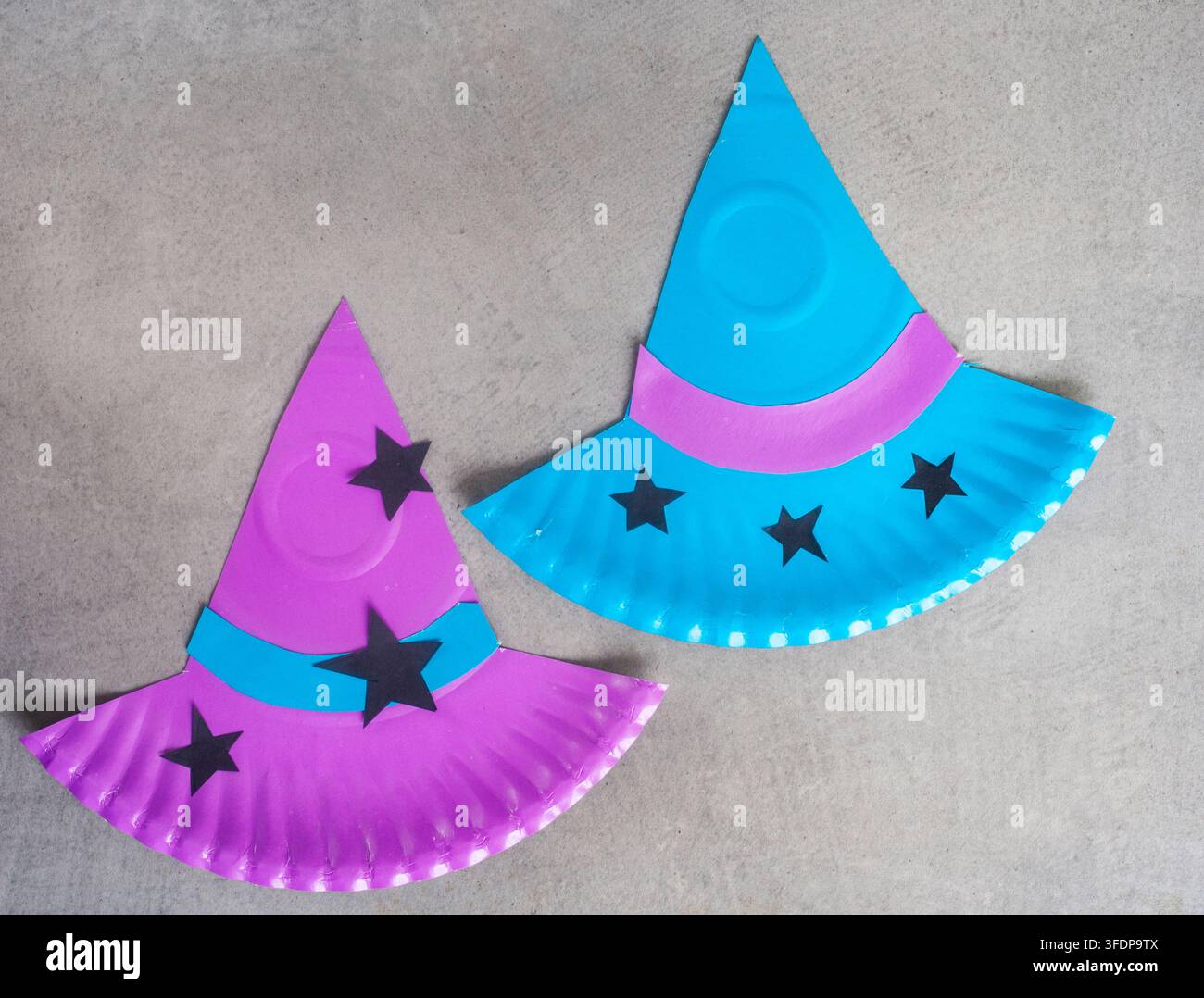Due cappelli da strega per Halloween fatti a mano con piatti di carta colorati e decorati con fasce a contrasto e stelle nere. DIY Halloween luminoso e semplice Foto Stock