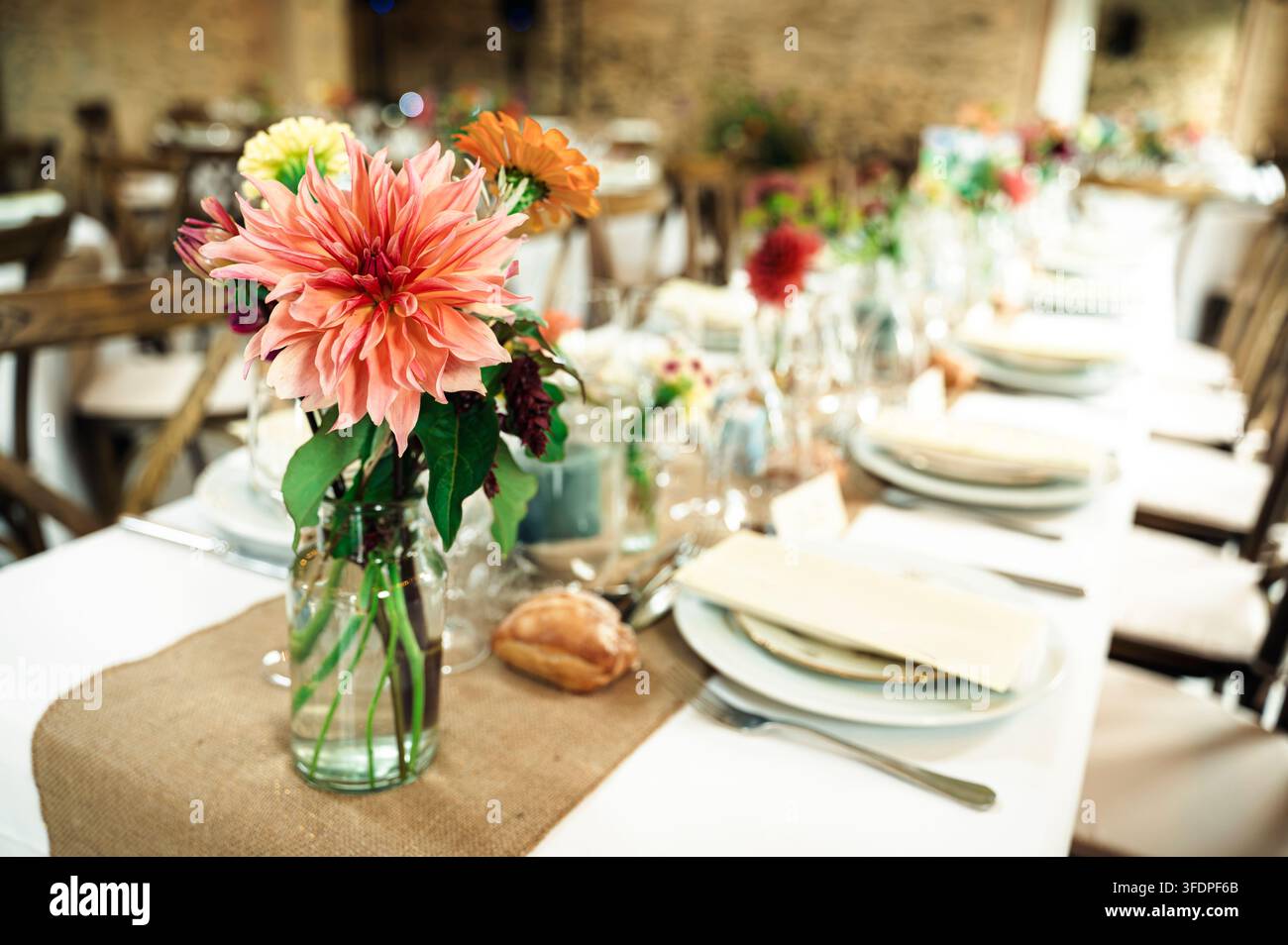 Elegante tavolo da ricevimento nuziale decorato con centrotavola floreali e apparecchiature. Foto Stock