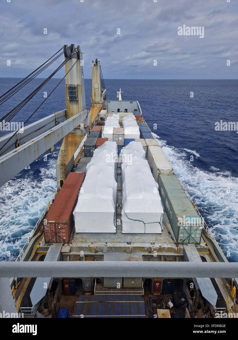 Nave portacontaineri che trasporti trasformatori industriali pesanti nella stiva e carico sul ponte durante operazioni logistiche marittime Foto Stock