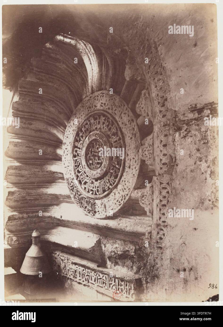 Un dettaglio architettonico in pietra scolpita dalla Moschea di al-Aqmar al Cairo, Egitto, con un medaglione circolare con motivi intricati, affiancato da elementi in pietra a strati a forma di ventaglio, di Beniamino Facchinelli, un fotografo italiano, alla fine del XIX secolo. Foto Stock
