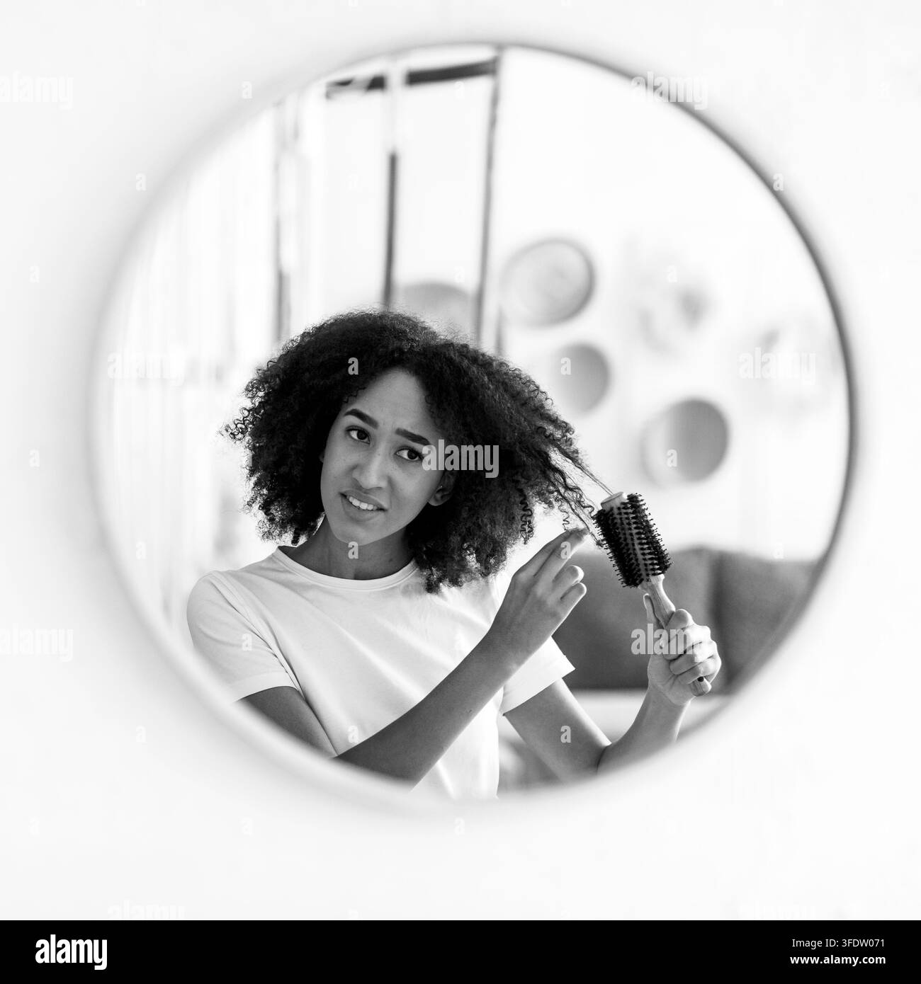 Irritato stressato attraente giovane signora spazzolando i capelli aggrovigliati in bagno Foto Stock