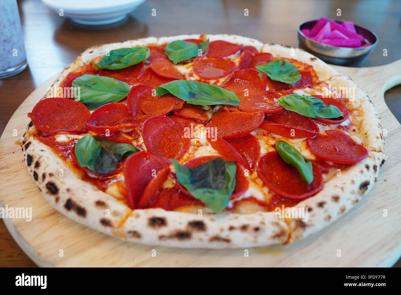 Pizza fatta in casa con pepperoni appena cotta con condimenti al basilico e sottaceti Foto Stock