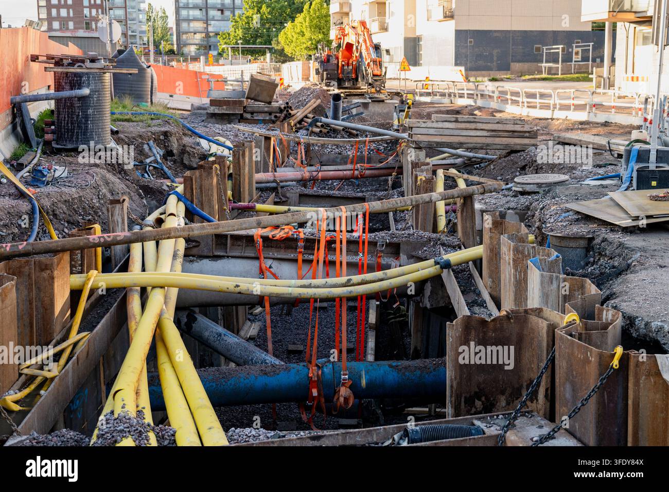 Cantiere edile urbano con tubi utilitari sotterranei esposti e infrastrutture di trincea durante la ricostruzione stradale Foto Stock