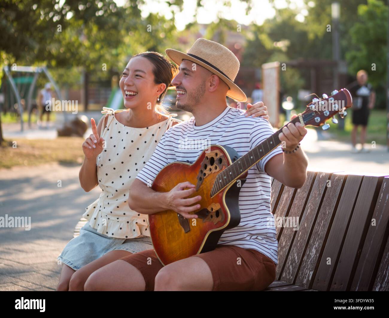 Momento romantico all'aperto mentre un uomo canta per la sua compagna con una chitarra acustica Foto Stock