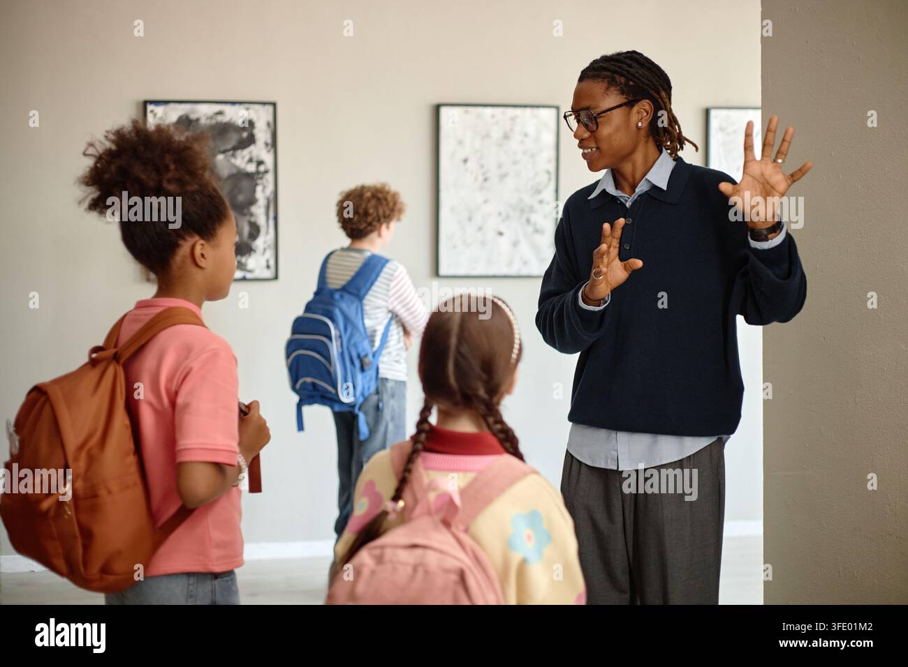 Guida del museo uomo nero che parla ai bambini durante una gita in una galleria d'arte Foto Stock