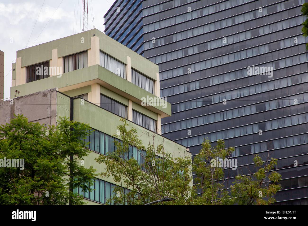 contrasto architettonico tra un edificio razionalista moderno a bassa altezza in primo piano e un grattacielo Foto Stock