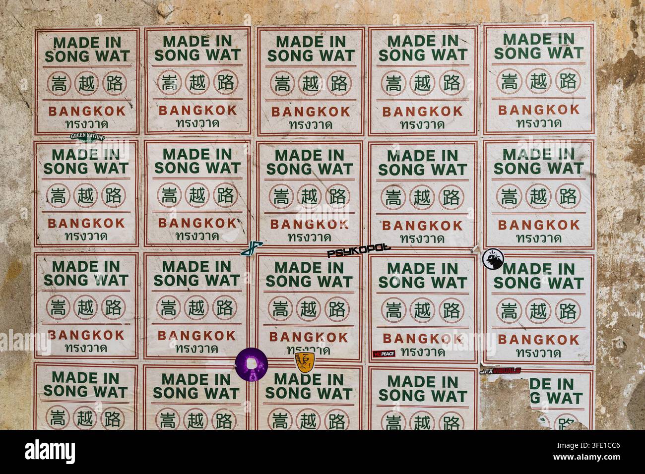 Posteri ripetuti Made in Song Wat su un muro eroso di Bangkok Foto Stock