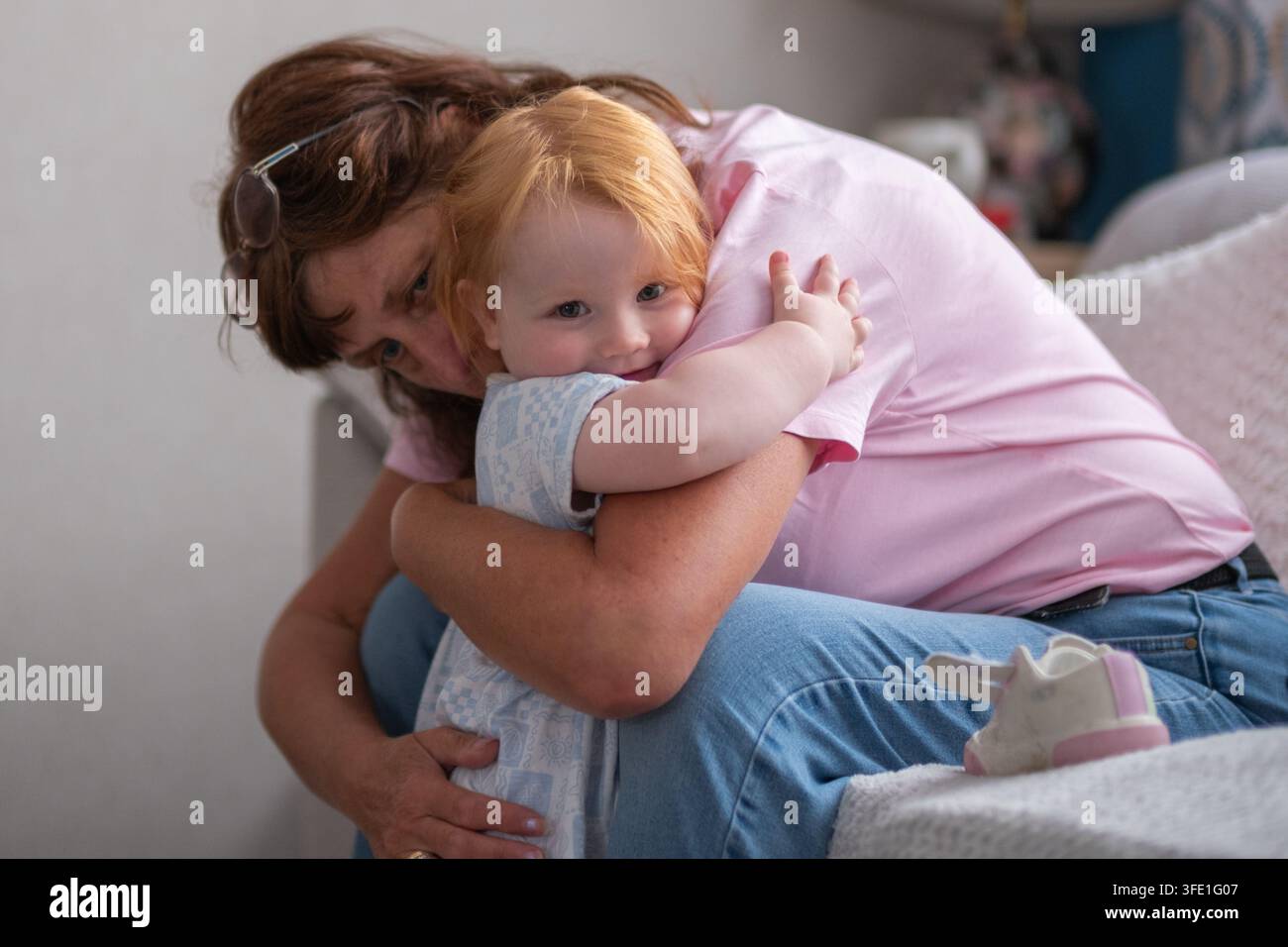 Nipote che abbraccia sua nonna con un sorriso sul viso Foto Stock