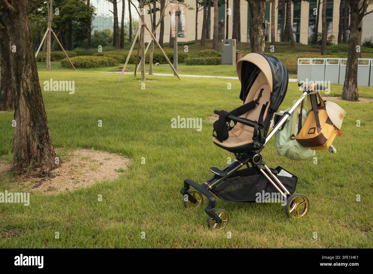 Un passeggino moderno con borse sospese si trova su un prato erboso in un parco tranquillo. Parco Botanico di Seoul, Corea del Sud Foto Stock