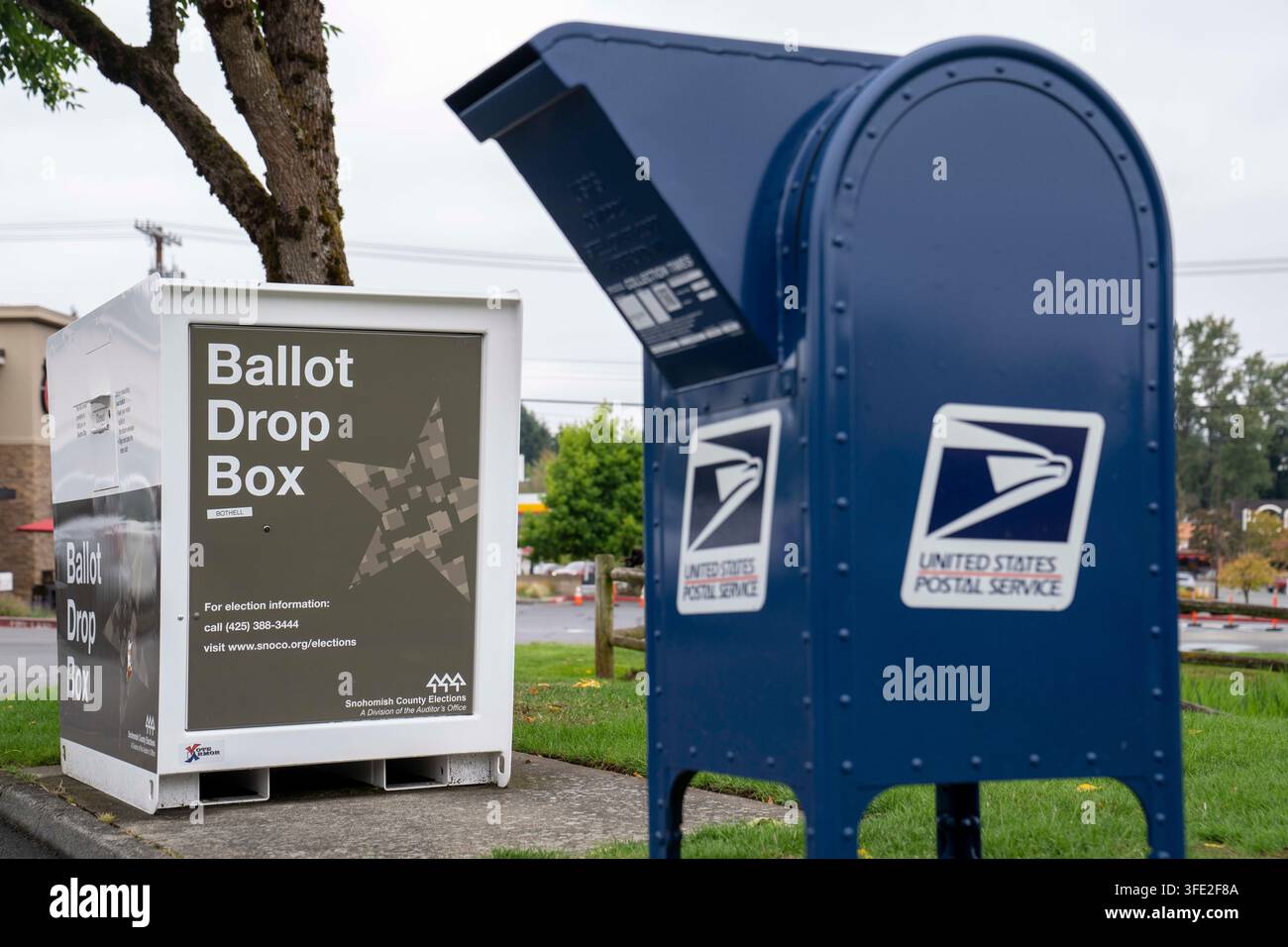 Bothell, Washington, USA. 1 set., 2026. Una cassetta di raccolta USPS blu si trova accanto a una cabina per il deposito delle schede elettorali della contea di Snohomish al margine di un parcheggio a Bothell, Washington, USA, martedì 1 settembre 2026. Oltre il 98% degli elettori dello stato di Washington utilizza il sistema di voto per posta, anche se una grande percentuale di elettori utilizza cabine per il deposito delle schede elettorali come questa invece di inviarle tramite il servizio postale. La fessura per l'inserimento ha un cartello "chiuso" perché non è in corso un'elezione attiva. L'amministrazione Trump ha cercato di limitare il voto per posta attraverso ordini esecutivi e nuove regole su come le Foto Stock