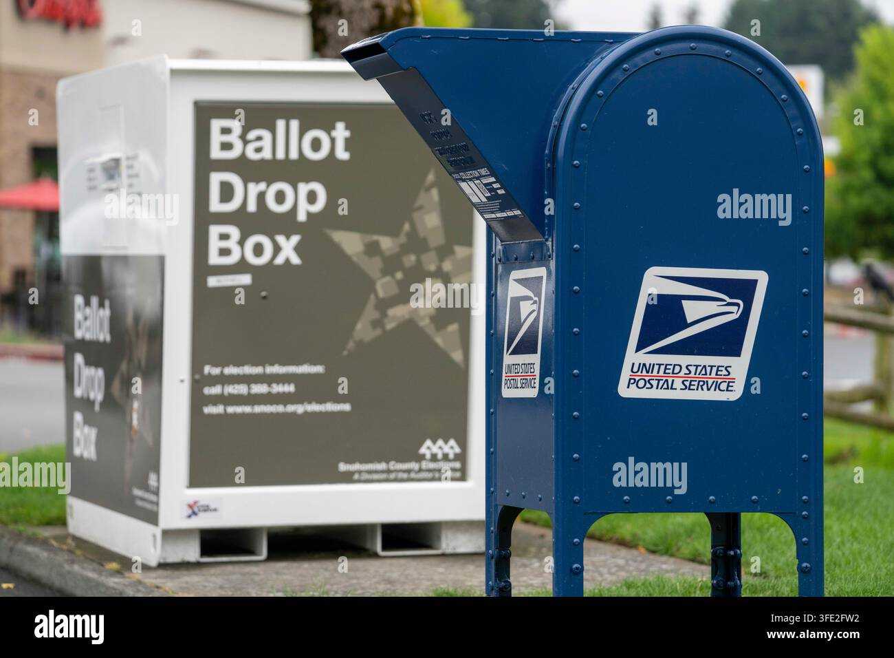 Bothell, Washington, USA. 1 set., 2026. Una cassetta di raccolta USPS blu si trova accanto a una cabina per il deposito delle schede elettorali della contea di Snohomish al margine di un parcheggio a Bothell, Washington, USA, martedì 1 settembre 2026. Oltre il 98% degli elettori dello stato di Washington utilizza il sistema di voto per posta, anche se una grande percentuale di elettori utilizza cabine per il deposito delle schede elettorali come questa invece di inviarle tramite il servizio postale. La fessura per l'inserimento ha un cartello "chiuso" perché non è in corso un'elezione attiva. L'amministrazione Trump ha cercato di limitare il voto per posta attraverso ordini esecutivi e nuove regole su come le Foto Stock