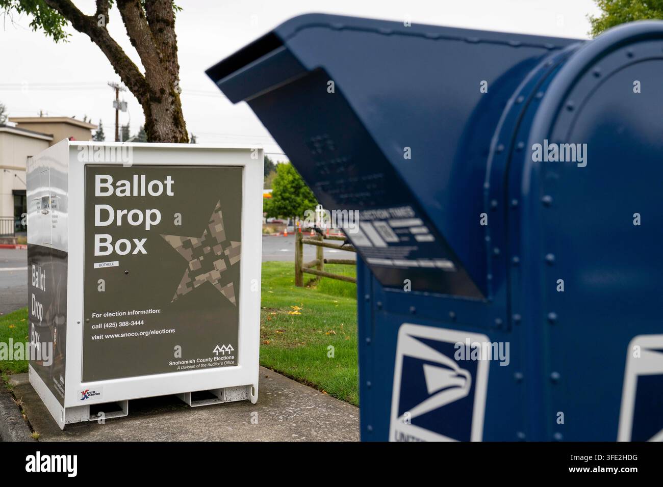 Bothell, Washington, USA. 1 set., 2026. Una cassetta di raccolta USPS blu si trova accanto a una cabina per il deposito delle schede elettorali della contea di Snohomish al margine di un parcheggio a Bothell, Washington, USA, martedì 1 settembre 2026. Oltre il 98% degli elettori dello stato di Washington utilizza il sistema di voto per posta, anche se una grande percentuale di elettori utilizza cabine per il deposito delle schede elettorali come questa invece di inviarle tramite il servizio postale. La fessura per l'inserimento ha un cartello "chiuso" perché non è in corso un'elezione attiva. L'amministrazione Trump ha cercato di limitare il voto per posta attraverso ordini esecutivi e nuove regole su come le Foto Stock