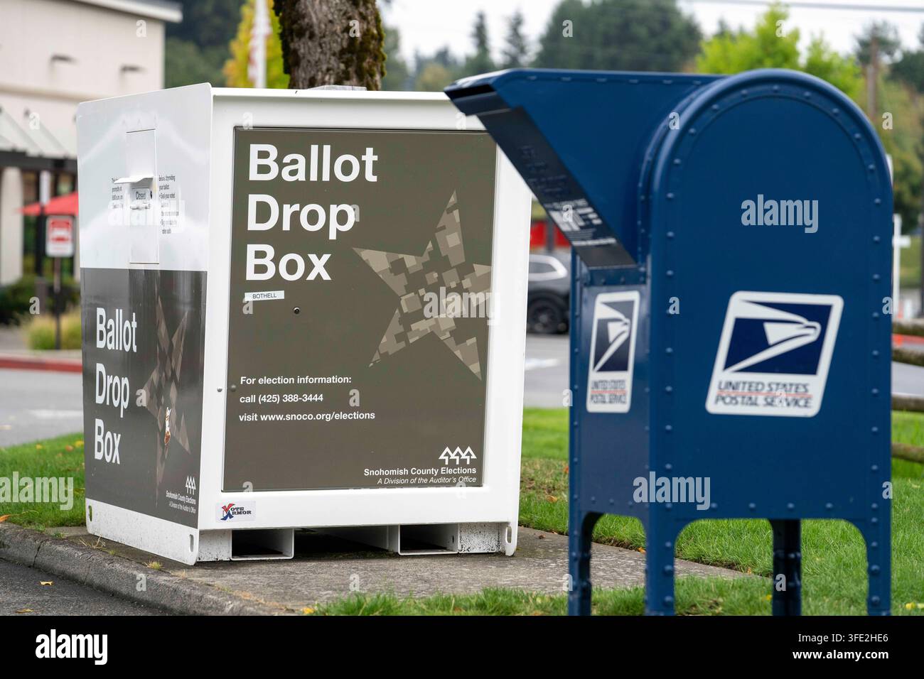 Bothell, Washington, USA. 1 set., 2026. Una cassetta di raccolta USPS blu si trova accanto a una cabina per il deposito delle schede elettorali della contea di Snohomish al margine di un parcheggio a Bothell, Washington, USA, martedì 1 settembre 2026. Oltre il 98% degli elettori dello stato di Washington utilizza il sistema di voto per posta, anche se una grande percentuale di elettori utilizza cabine per il deposito delle schede elettorali come questa invece di inviarle tramite il servizio postale. La fessura per l'inserimento ha un cartello "chiuso" perché non è in corso un'elezione attiva. L'amministrazione Trump ha cercato di limitare il voto per posta attraverso ordini esecutivi e nuove regole su come le Foto Stock