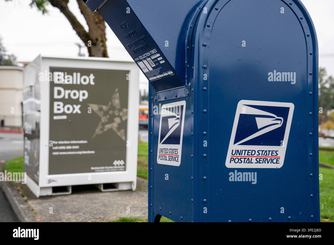 Bothell, Washington, USA. 1 set., 2026. Una cassetta di raccolta USPS blu si trova accanto a una cabina per il deposito delle schede elettorali della contea di Snohomish al margine di un parcheggio a Bothell, Washington, USA, martedì 1 settembre 2026. Oltre il 98% degli elettori dello stato di Washington utilizza il sistema di voto per posta, anche se una grande percentuale di elettori utilizza cabine per il deposito delle schede elettorali come questa invece di inviarle tramite il servizio postale. La fessura per l'inserimento ha un cartello "chiuso" perché non è in corso un'elezione attiva. L'amministrazione Trump ha cercato di limitare il voto per posta attraverso ordini esecutivi e nuove regole su come le Foto Stock