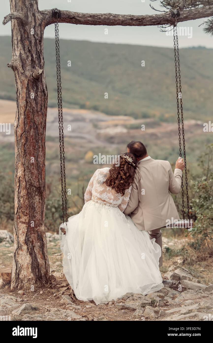 Abbraccio nuziale nell'amore su un'altalena Foto Stock