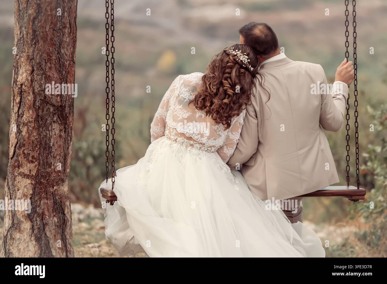 Abbraccio nuziale nell'amore su un'altalena Foto Stock