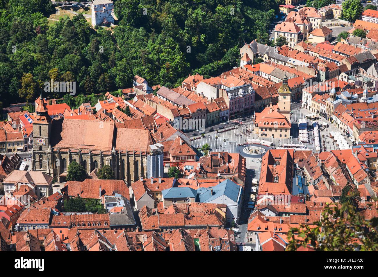 Vista aerea della vecchia città di Brasov con la Chiesa Nera e la Piazza del Consiglio dai tetti rossi circondati da colline boschive verdi, Brasov, Transilvania, Romania Foto Stock