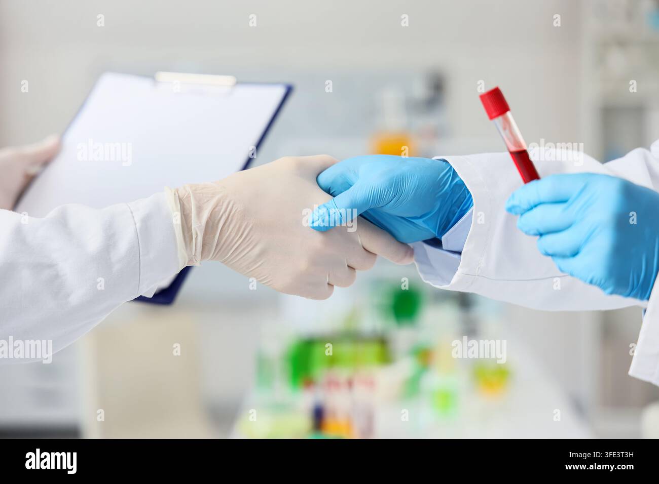 Chimici che si stringono la mano in laboratorio, primo piano Foto Stock