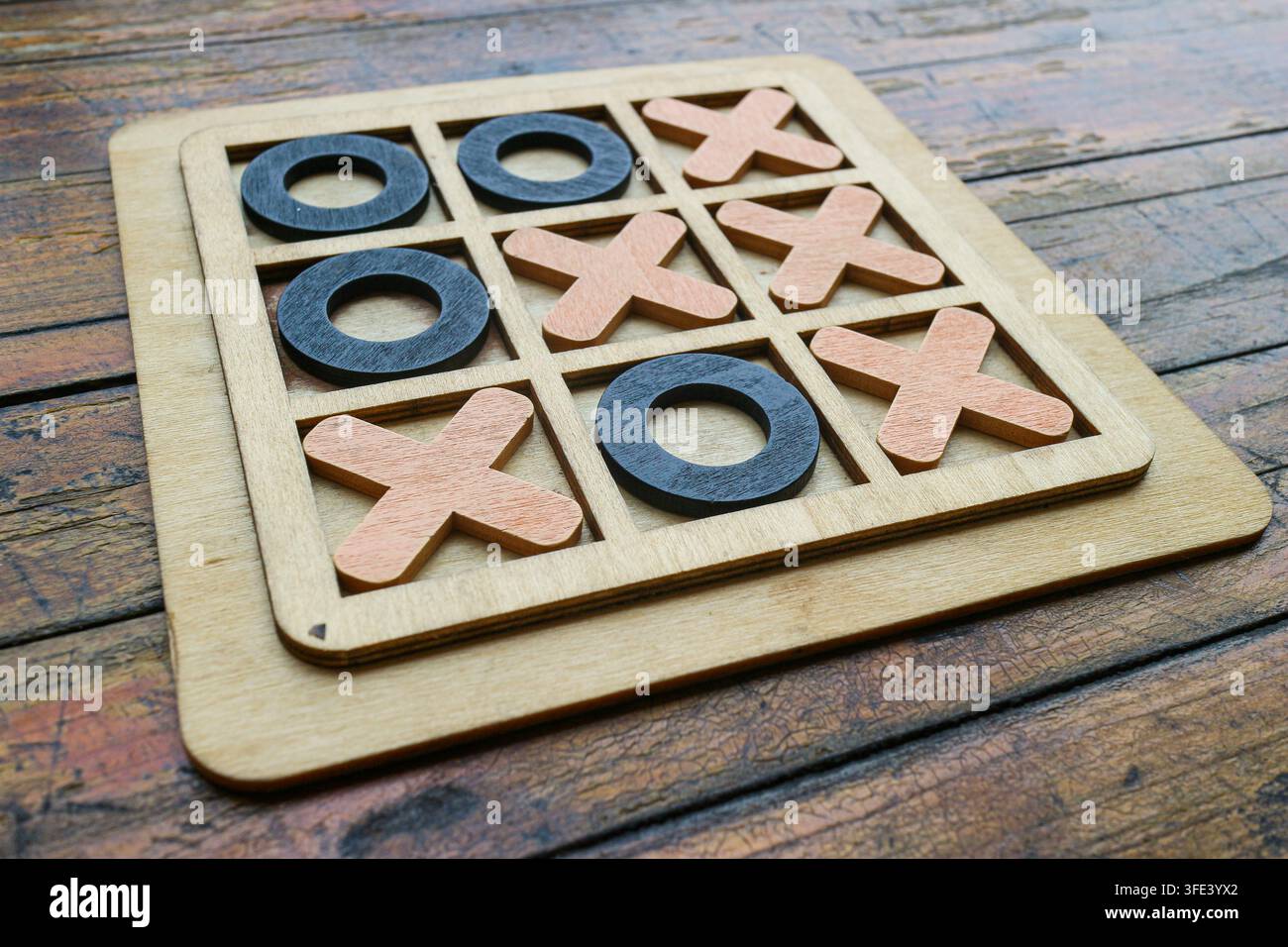 Prima angolata ravvicinata di una partita di Nulla e Croce in legno fatta a mano su un tavolo rustico graffiato che mostra una linea diagonale vincente Foto Stock