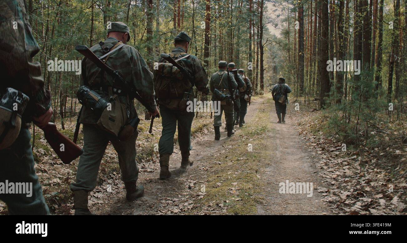 Squadra di soldati di fanteria tedeschi della Seconda Guerra Mondiale in marcia attraverso una foresta primaverile Foto Stock