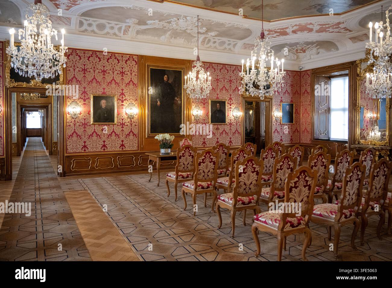 Fulda, Germania - 28 set. 25: Sala cerimoniale dello Stadtschloss Fu con lampadari di cristallo, pareti in damasco rosso, ritratti storici e sedie intagliate Foto Stock