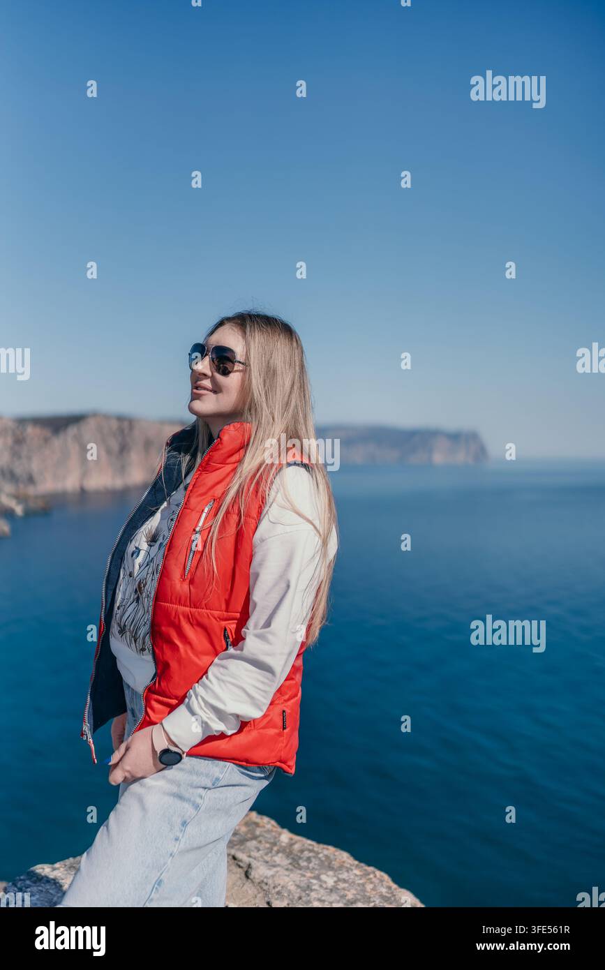 Donna in piedi su una sporgenza rocciosa che si affaccia sull'oceano azzurro con spazio per il testo in una giornata soleggiata Foto Stock