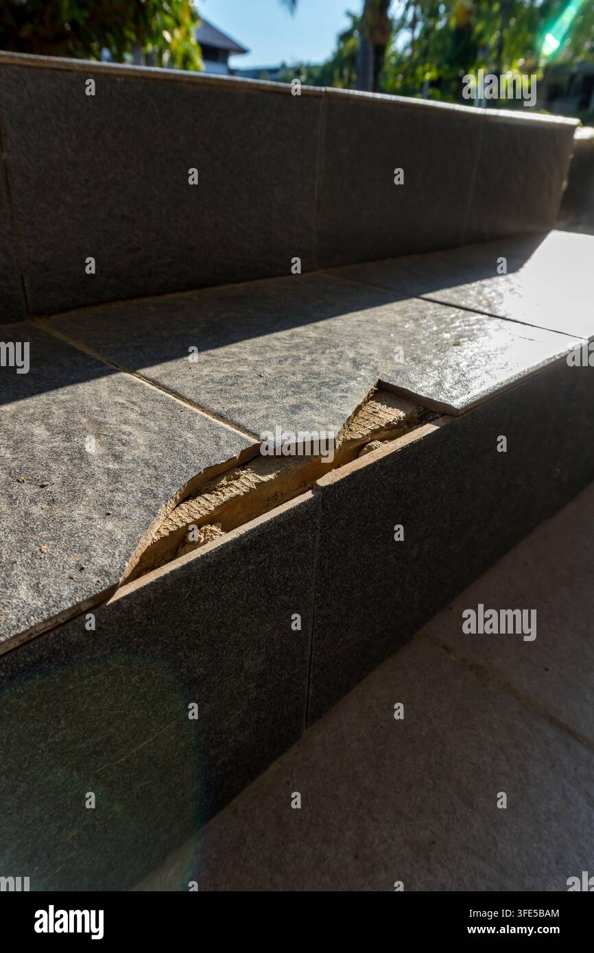 Scalinata danneggiata con piastrelle di ceramica grigio scuro rotte e malta esposta Foto Stock
