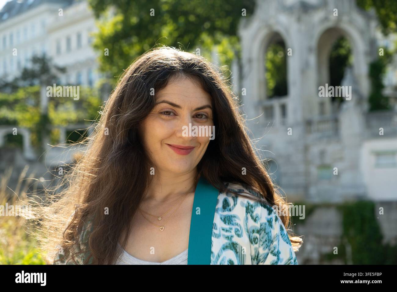 Primo piano di una bella donna bruna di mezza età che sorride alla luce del sole Foto Stock