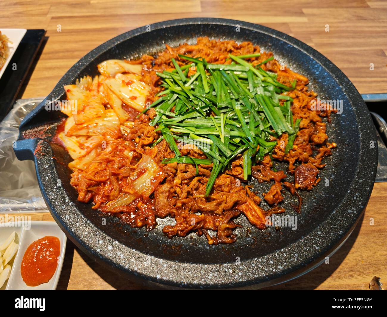 Un piatto tradizionale coreano di maiale speziato saltato con kimchi e erba cipollina fresca servito in Corea. Foto Stock