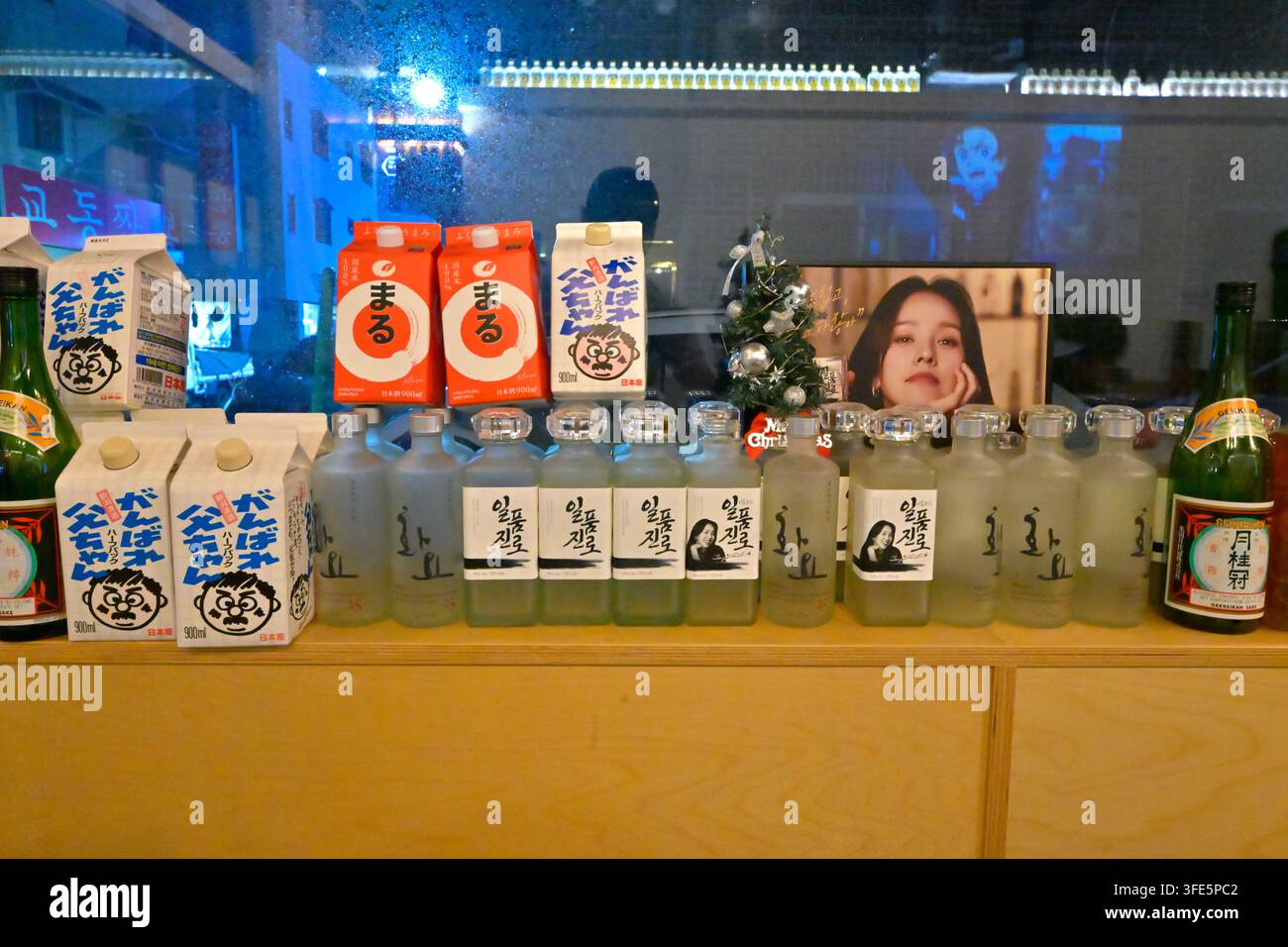 Una esposizione di bevande coreane assortite tra cui bottiglie di soju e cartoni di latte in un ambiente di bar coreano. Foto Stock