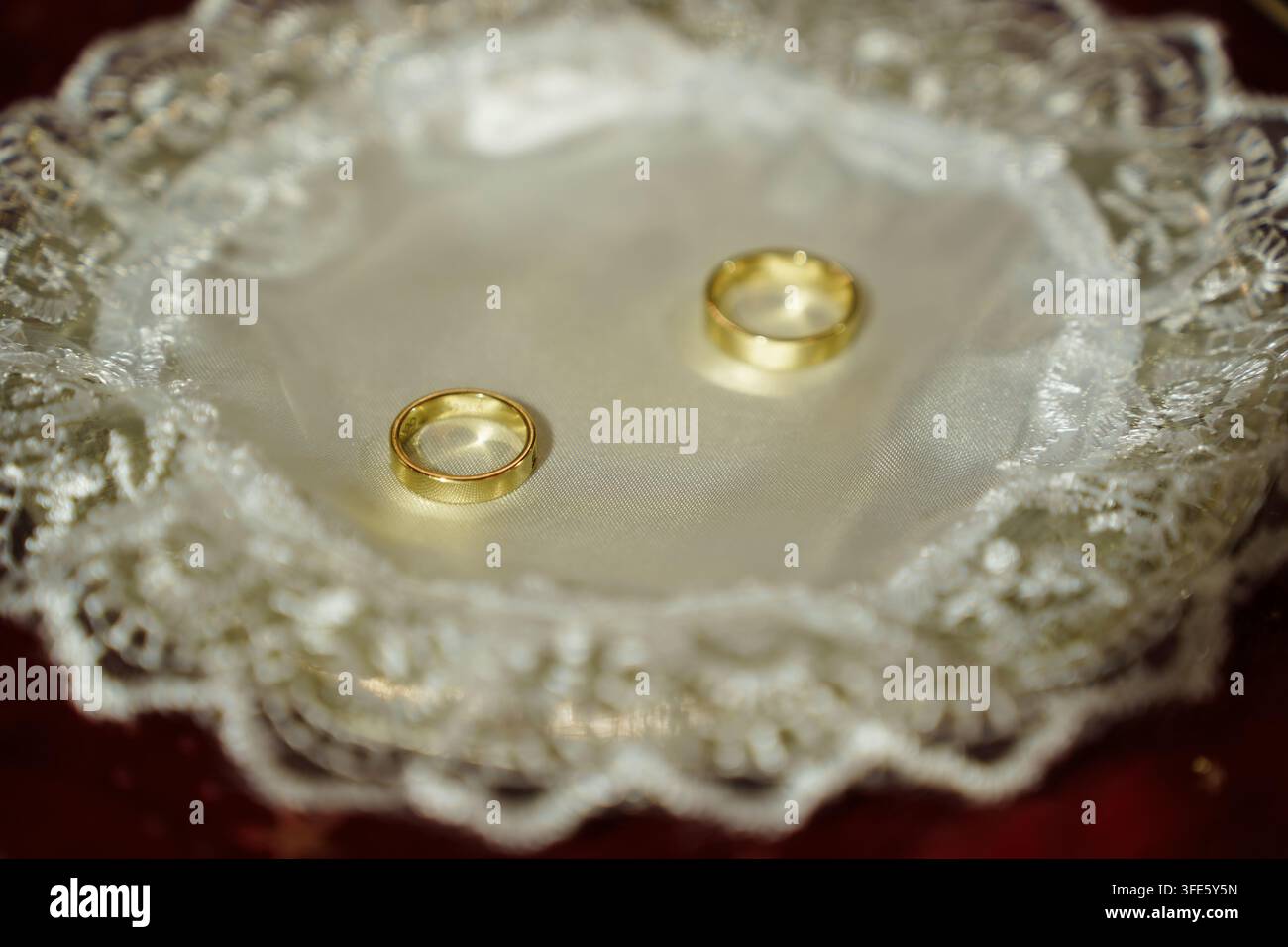 Due anelli d'oro posizionati su un delicato centrino di pizzo, che rappresentano temi di matrimonio, unione, amore e cerimonia nuziale con un'atmosfera romantica Foto Stock