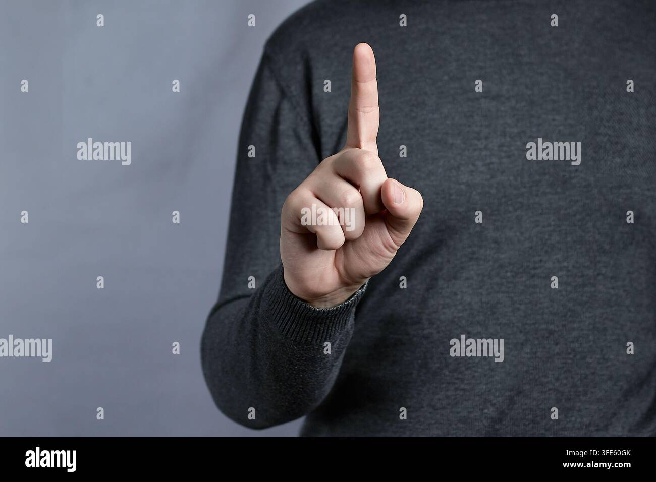 Prima piano di una mano che punta verso l'alto con il gesto dell'indice che mostra il numero uno e attira l'attenzione Foto Stock