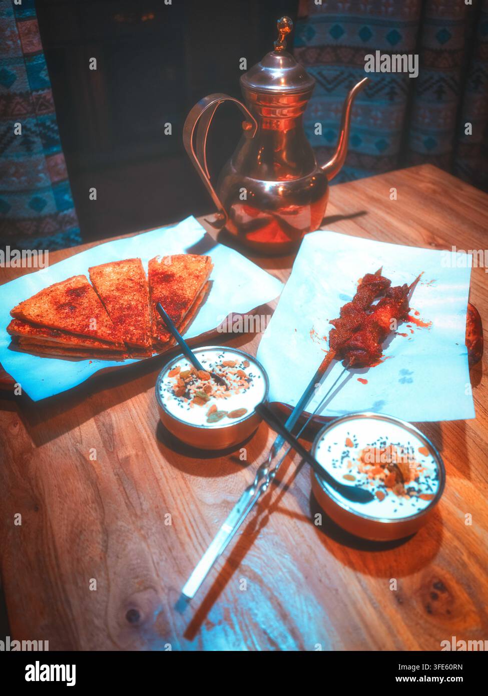 Cena in stile Xinjiang servita in un ristorante locale di Dunhuang Gansu. Spiedini di agnello alla griglia, naan speziato al forno, yogurt fatto in casa e pentola di rame vintage su Foto Stock
