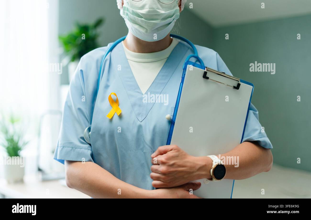 Infermiera e medico compassionevoli tengono una clipboard indossando un nastro giallo che simboleggia la consapevolezza del cancro infantile. Operatore sanitario dedicato che sostiene i bambini in un ambiente ospedaliero. Foto Stock