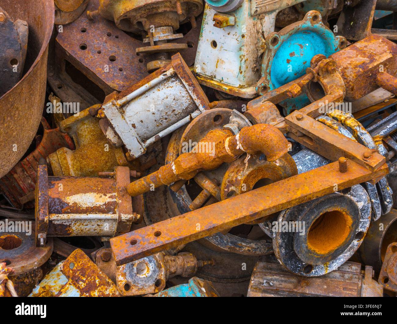 Prima vista di un grande mucchio di componenti metallici industriali arrugginiti. Vari pezzi di macchinari, tubi e flange creano una composizione astratta e testurizzata. Foto Stock