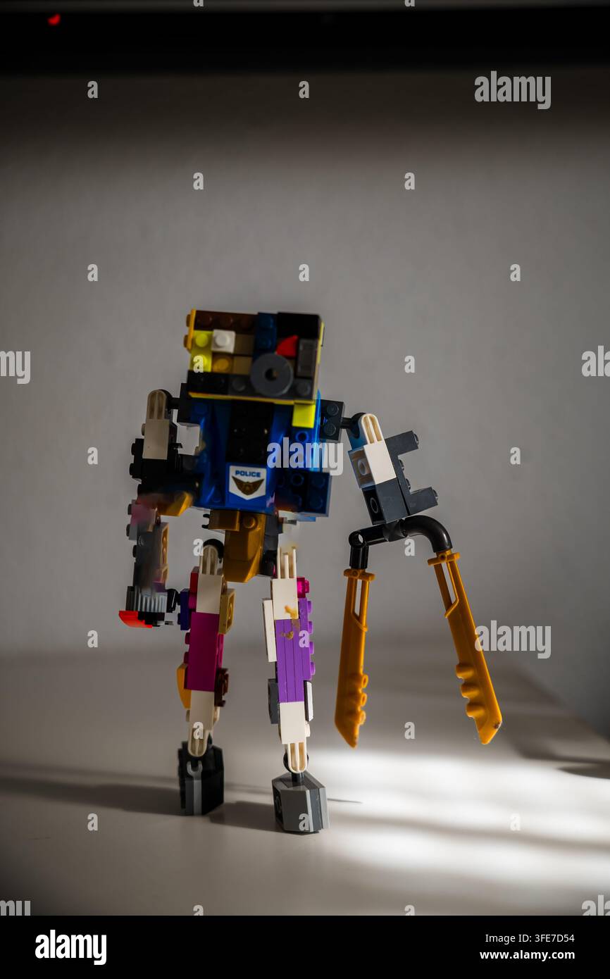 Figura di robot mech Lego personalizzata costruita con mattoncini di plastica assortiti, in piedi come una creazione di giocattolo unica su una superficie bianca del tavolo a casa. Foto Stock