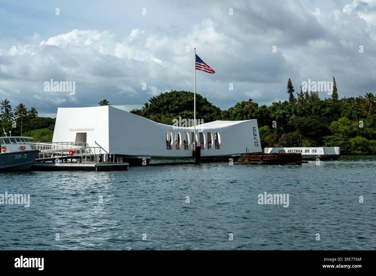 Pearl Harbor, Hawaii - Gennaio 2024: Il bianco Memoriale dell'USS Arizona si estende sulle reliquie della corazzata affondata, con una bandiera americana che sventola sopra e visitatori Foto Stock