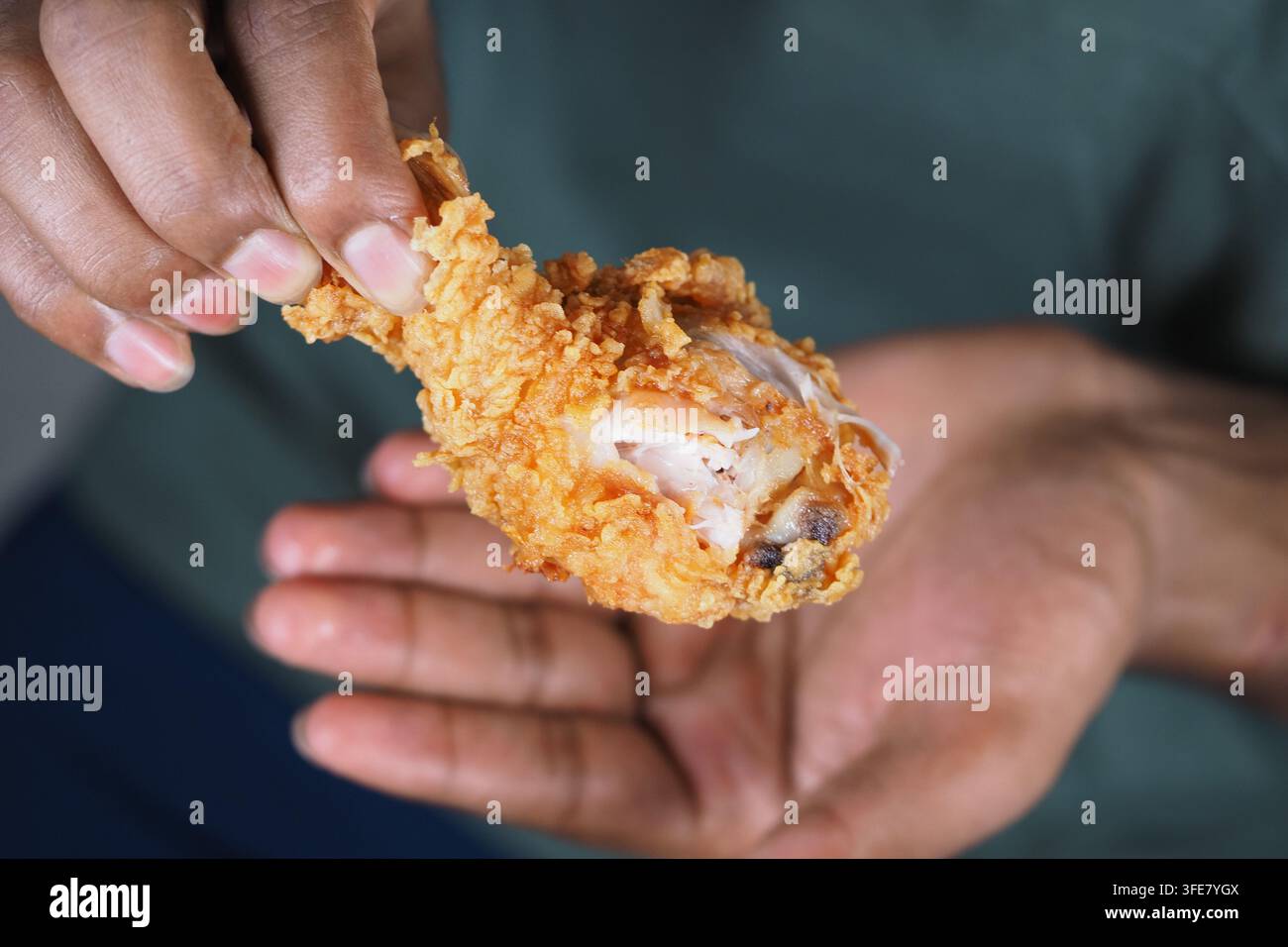 Tenendo in mano un pezzo di pollo fritto Foto Stock