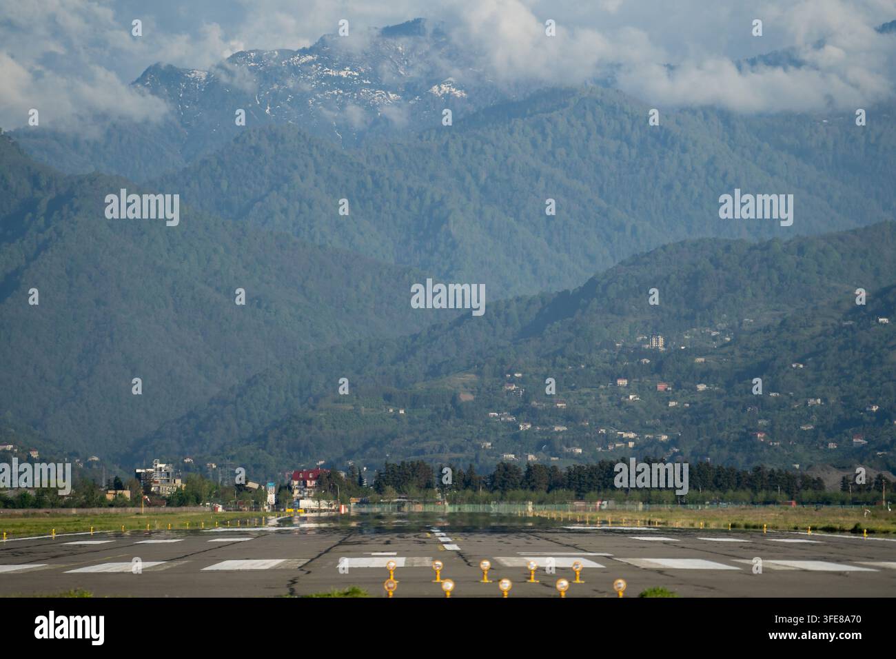 La pista di atterraggio dell'aeroporto conduce verso le montagne del Caucaso coperte di nuvole fuori dalla città di Batumi in Georgia Foto Stock