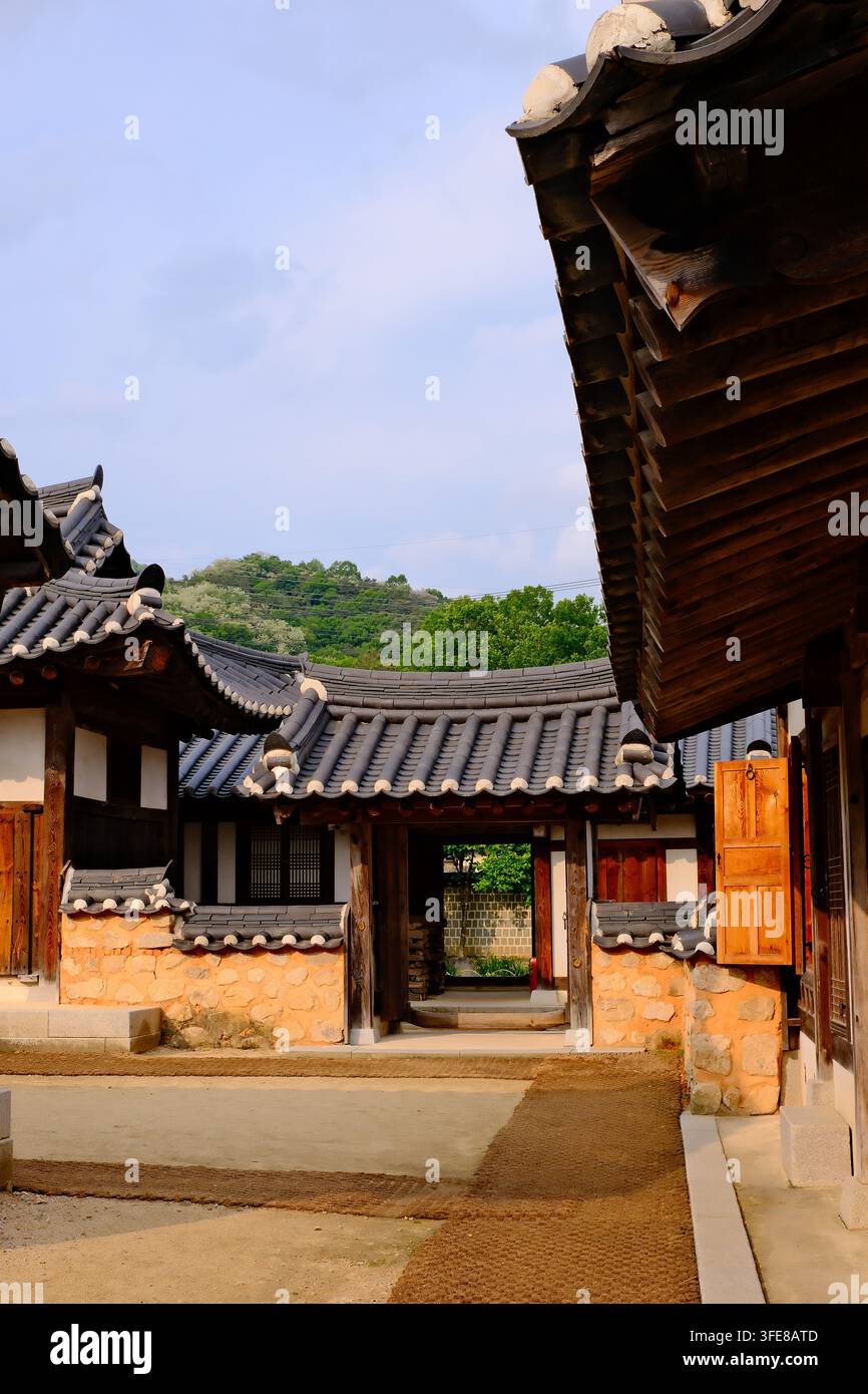 Edifici hanok tradizionali coreani con tetti di tegole e porte di legno in Corea, sullo sfondo di una montagna verde. Foto Stock