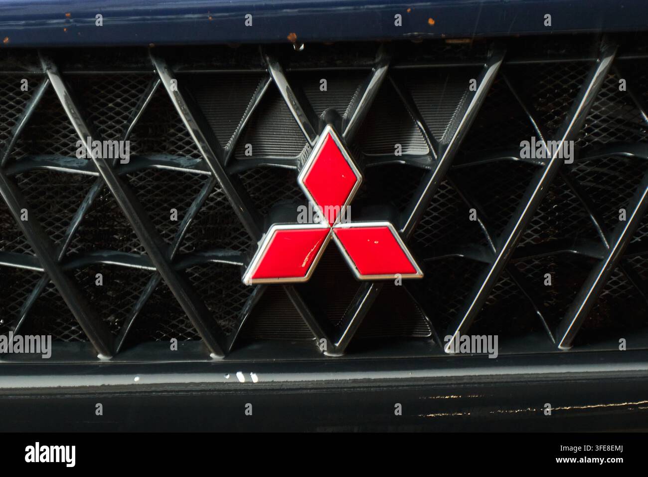 Tyumen, Russia-10 luglio 2026: Primo piano dell’iconico emblema rosso a tre diamanti Mitsubishi montato su una griglia nera texture Foto Stock